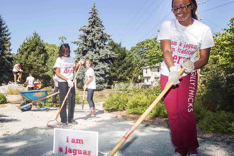 IUPUI student volunteers spreading gravel with rakes for iServe day