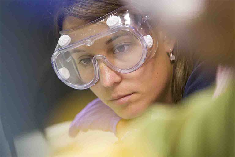 Close-up of a female IUPUI student wearing goggles in a lab environment