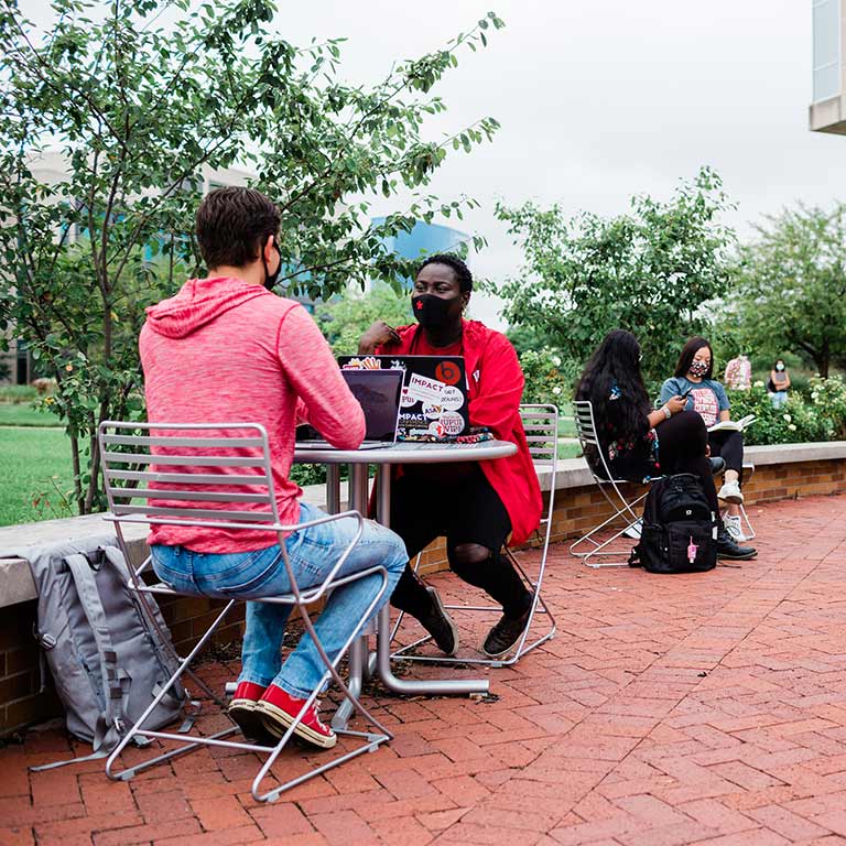 Students chat and study safely outside of IUPUI's University Library.